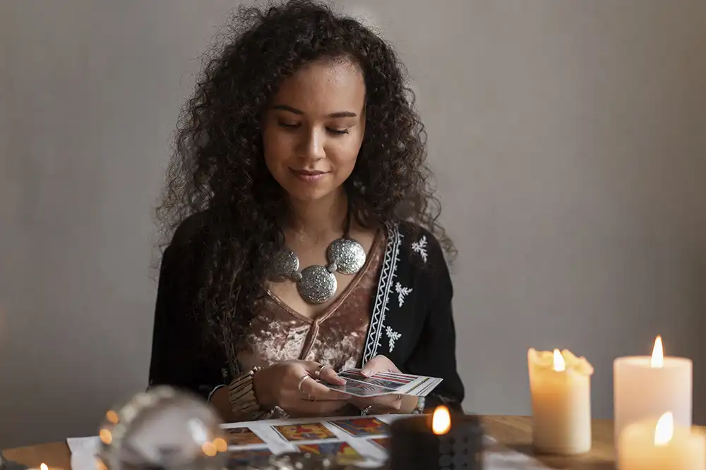 Vidente escolhendo cartas de tar&ocirc; junto a velas